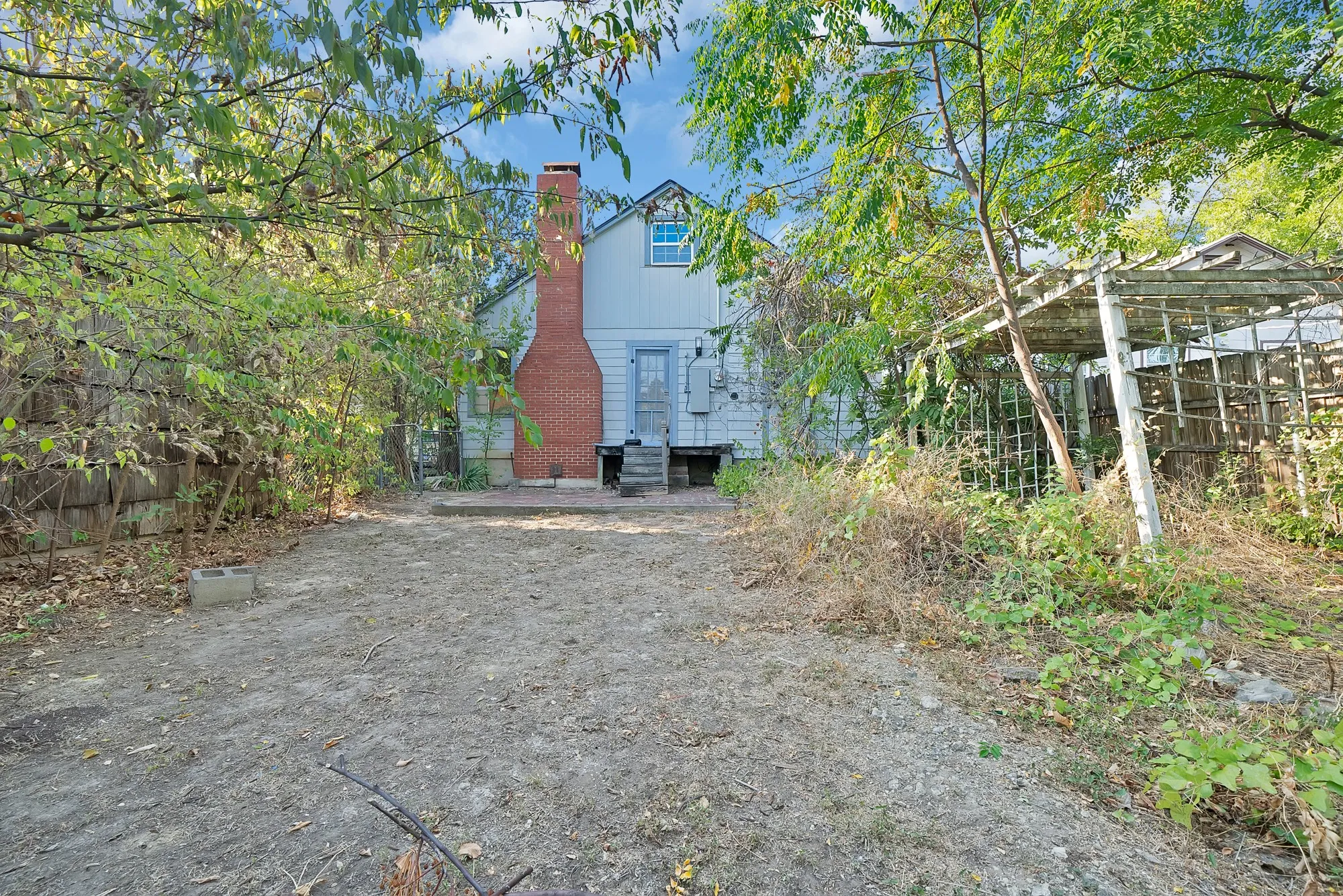 Rear exterior with a prominent brick chimney, multi-level siding, and a wooden deck