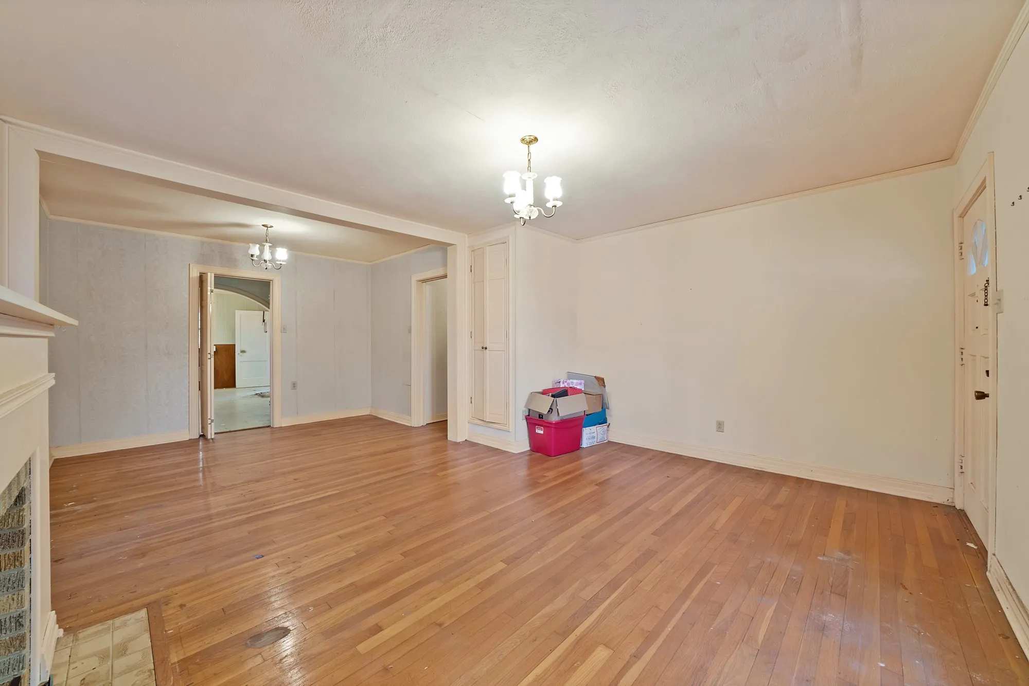 Hardwood flooring throughout, fireplace with brick surround, built-in storage, and ceiling-mounted light fixtures