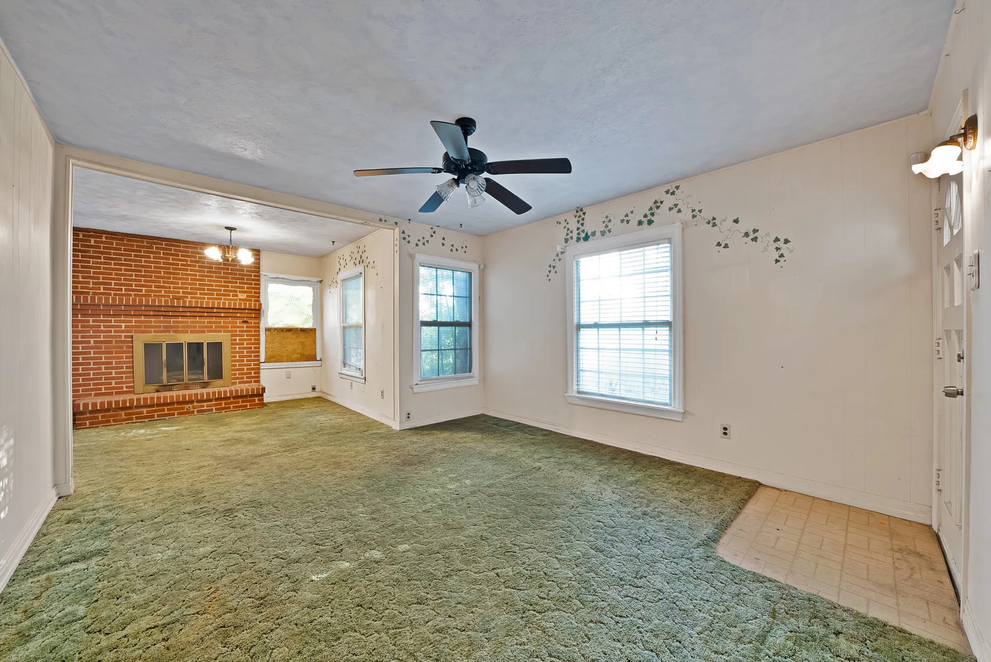 Spacious interior featuring a brick fireplace, ceiling fan, and multiple windows