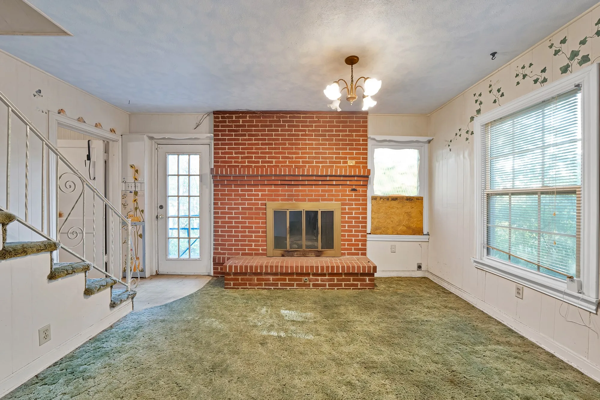 Brick fireplace with a raised hearth, multiple windows, and a glass-paneled exterior door