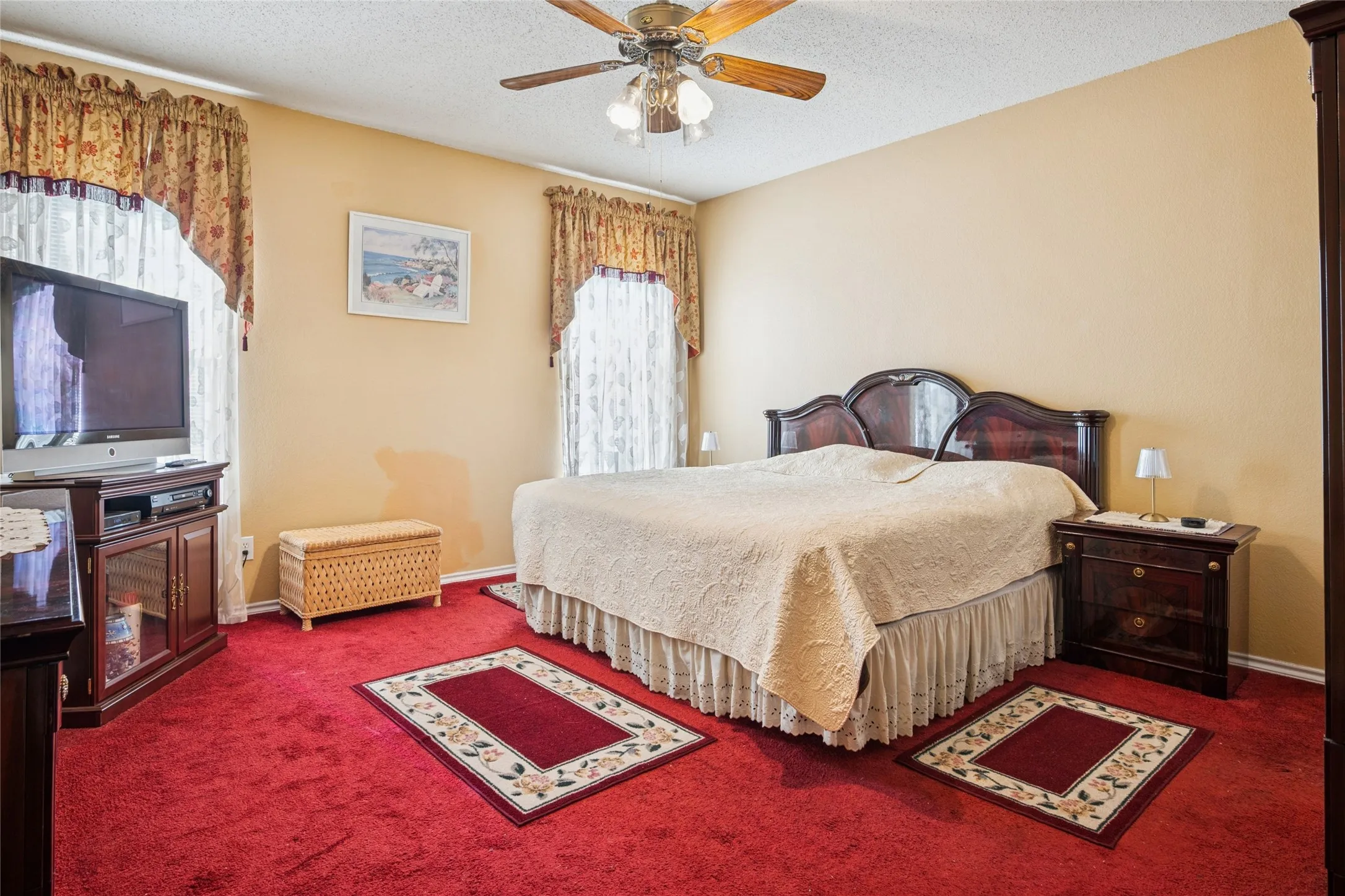 Bedroom featuring carpeting, two windows with valances, and a ceiling fan with light fixture