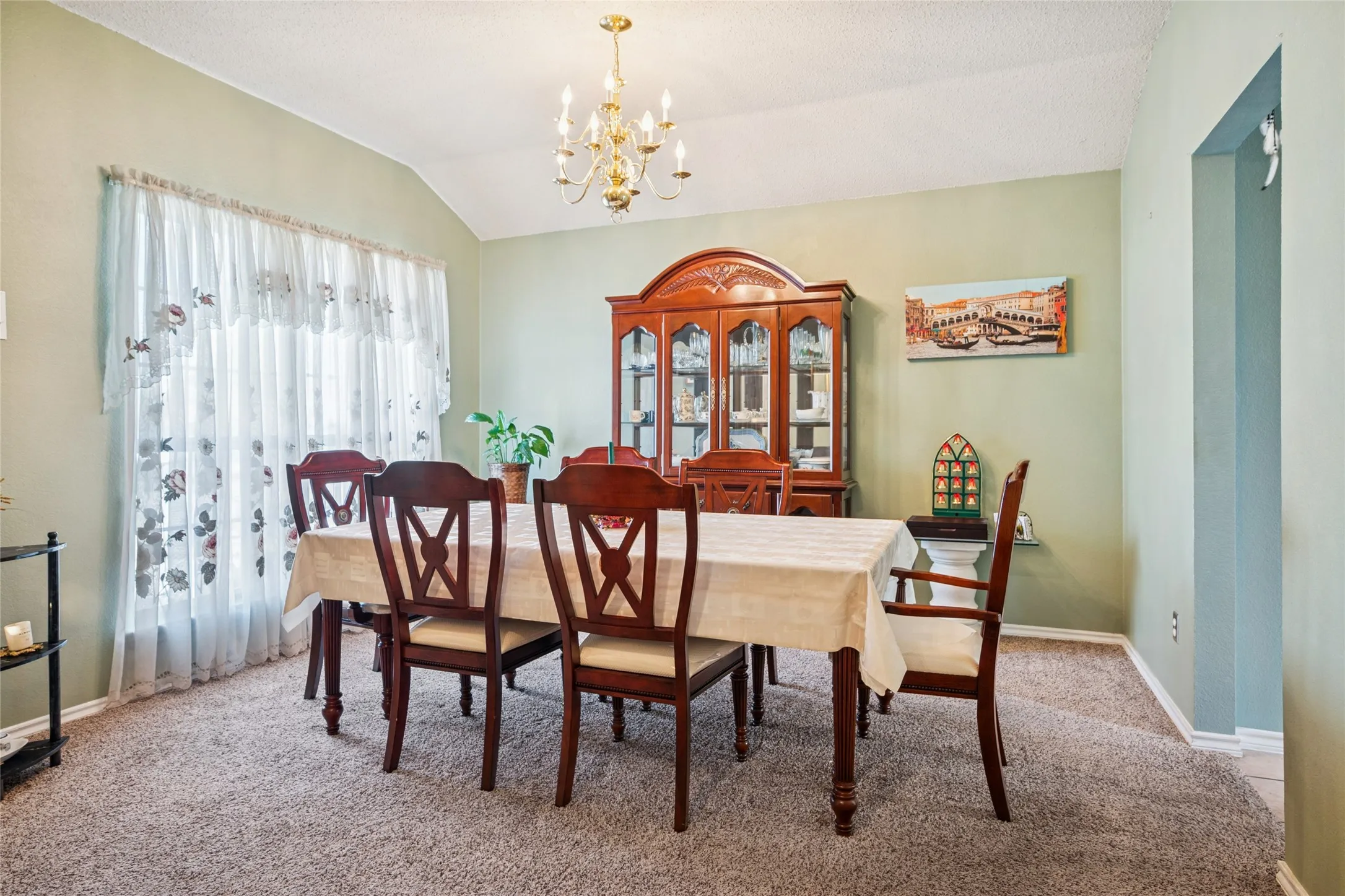 Vaulted ceiling with an ornate chandelier, wall-to-wall carpeting.