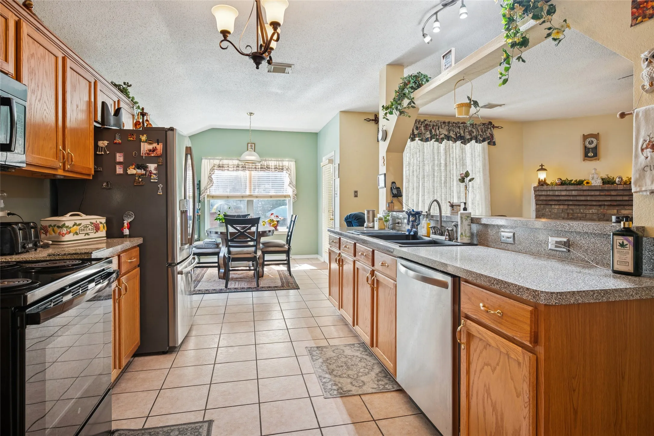 Kitchen featuring tile flooring, wood cabinetry, stone-finish countertops, stainless steel appliances, and a built-in breakfast bar