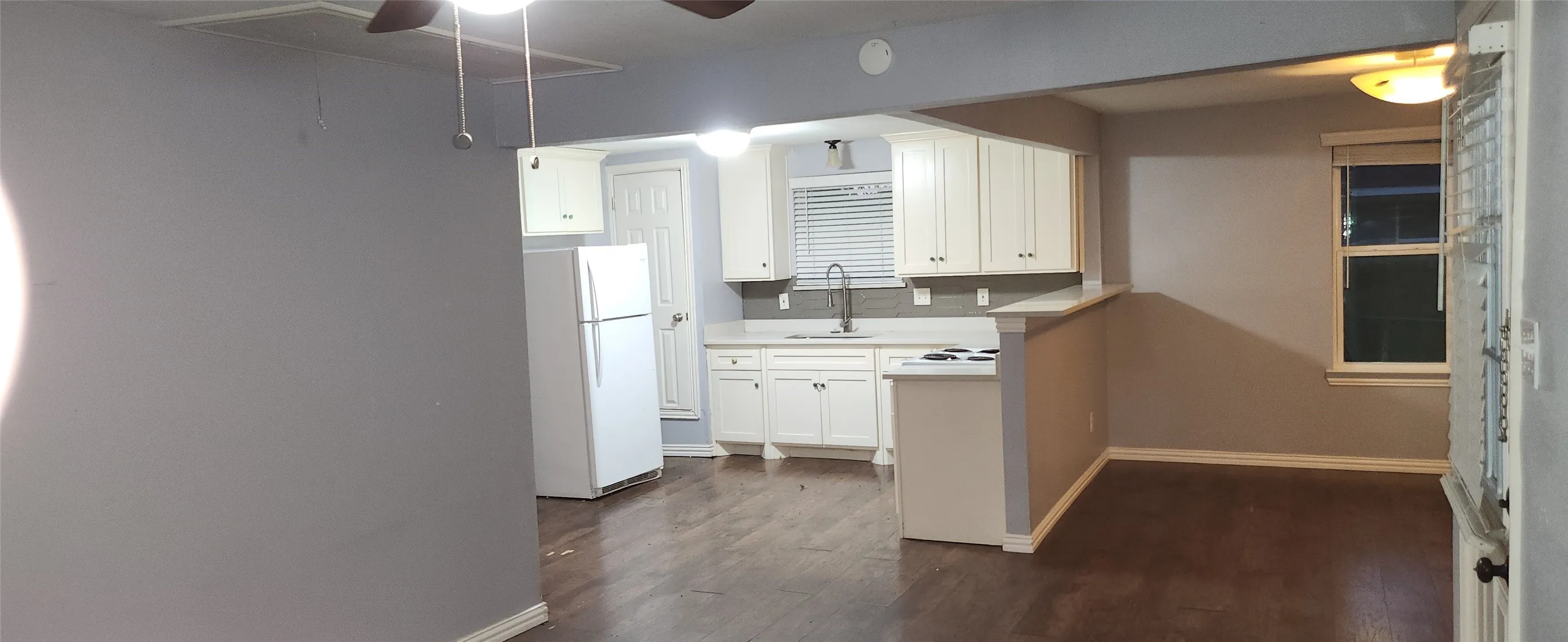 Kitchen featuring white cabinetry, gray tile backsplash, light countertops, and wood-finish flooring