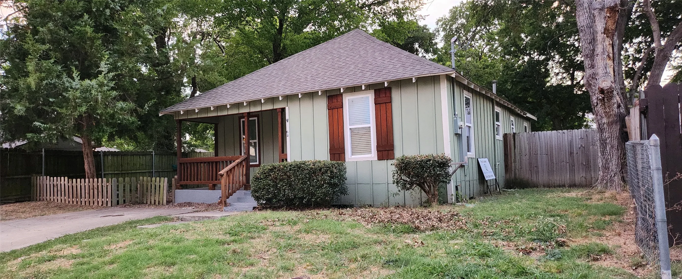 Single-story residence featuring light green siding and a covered front porch with wood railings