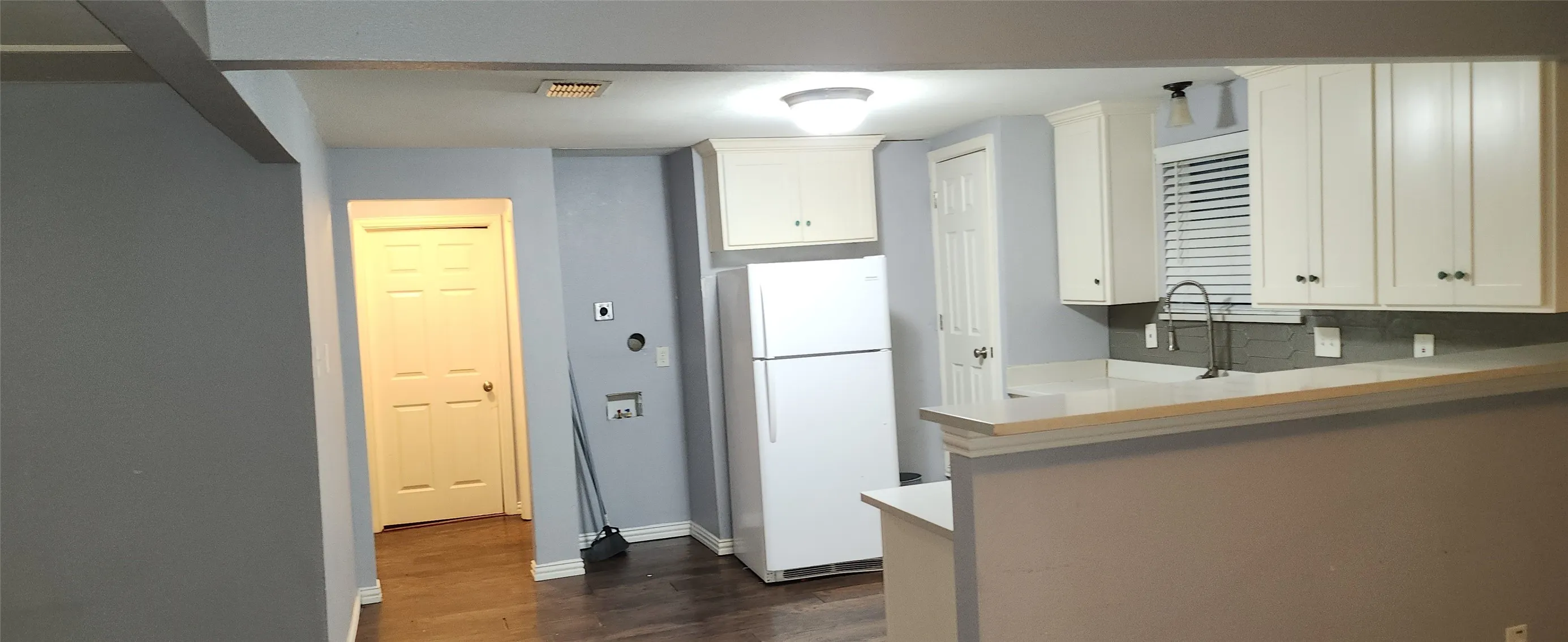 Kitchen area featuring white cabinetry, light countertops, and a tile backsplash