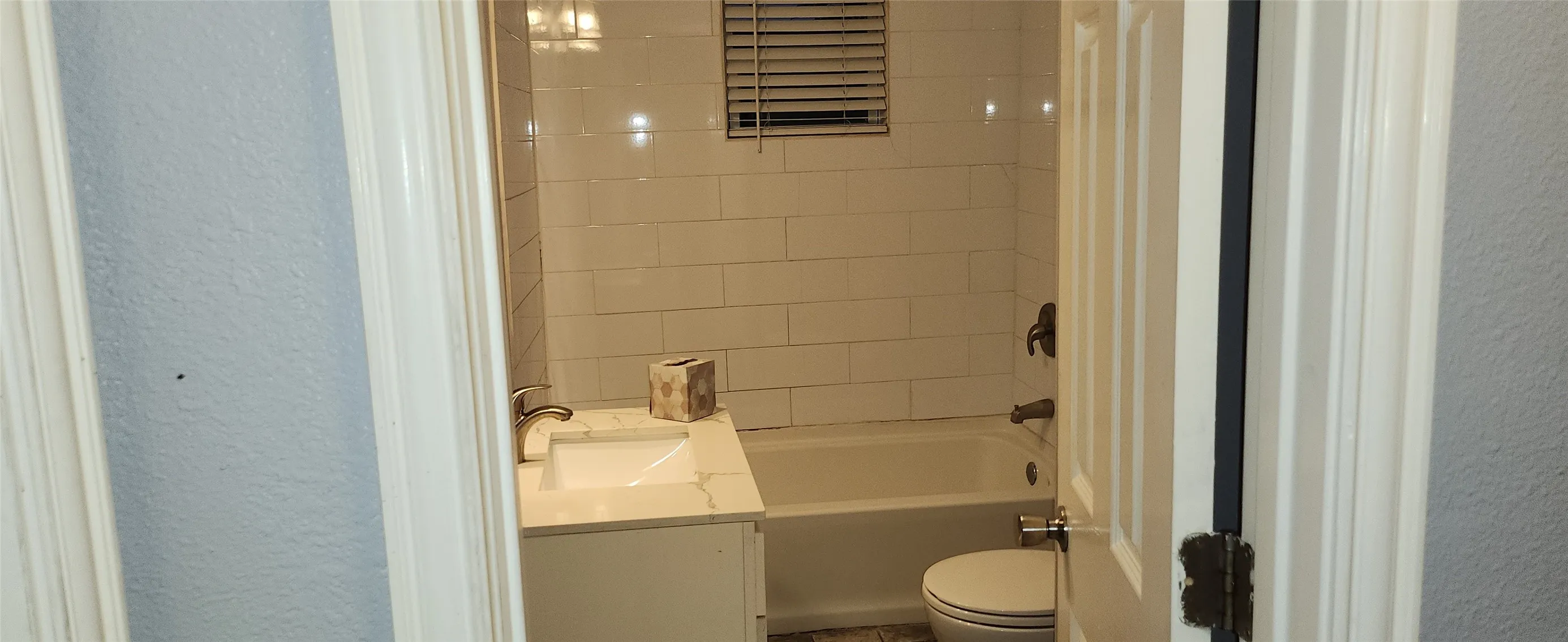 White subway tile shower surround, single vanity with integrated sink, white countertop, and brushed nickel faucet