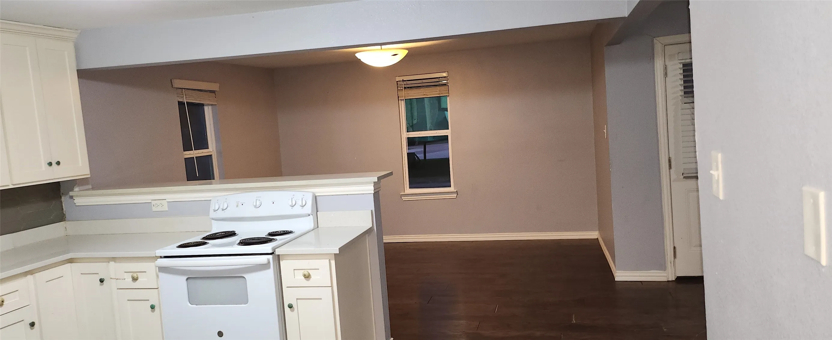 Kitchen featuring white cabinetry with dark hardware, a white electric range, and a breakfast bar