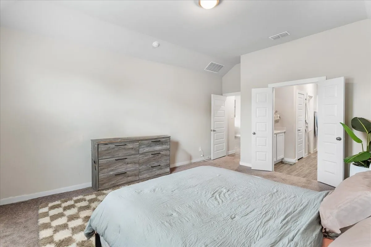 Carpeted bedroom with a vaulted ceiling and an overhead light fixture