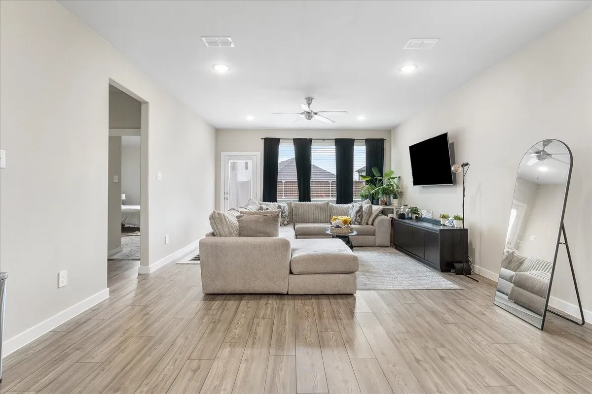 Open-concept living area featuring wood-finish flooring, recessed lighting, and a ceiling fan