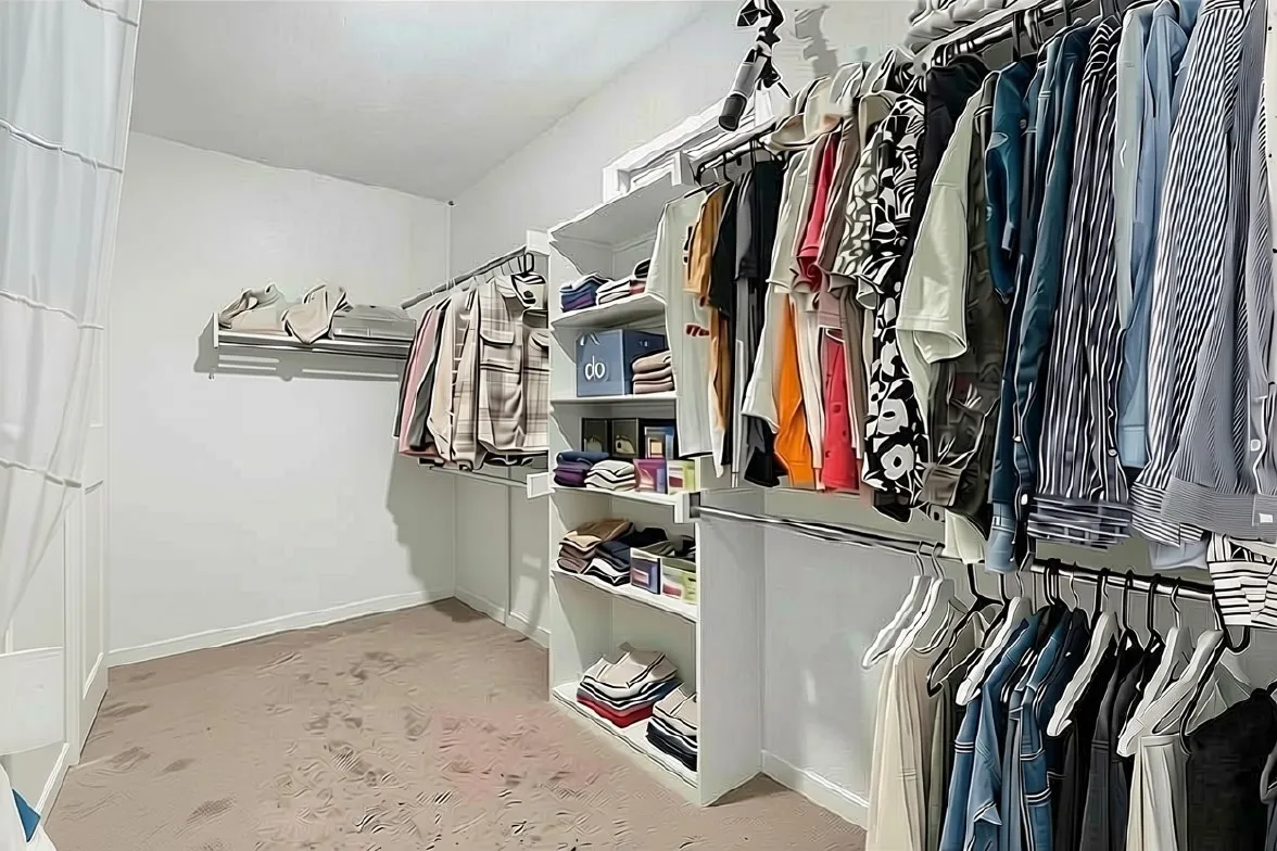 Built-in shelving, multiple hanging rods, and neutral carpeting