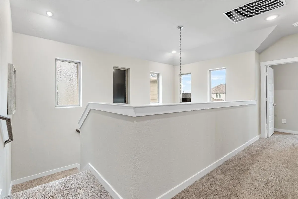 Open landing area with recessed lighting and multiple windows