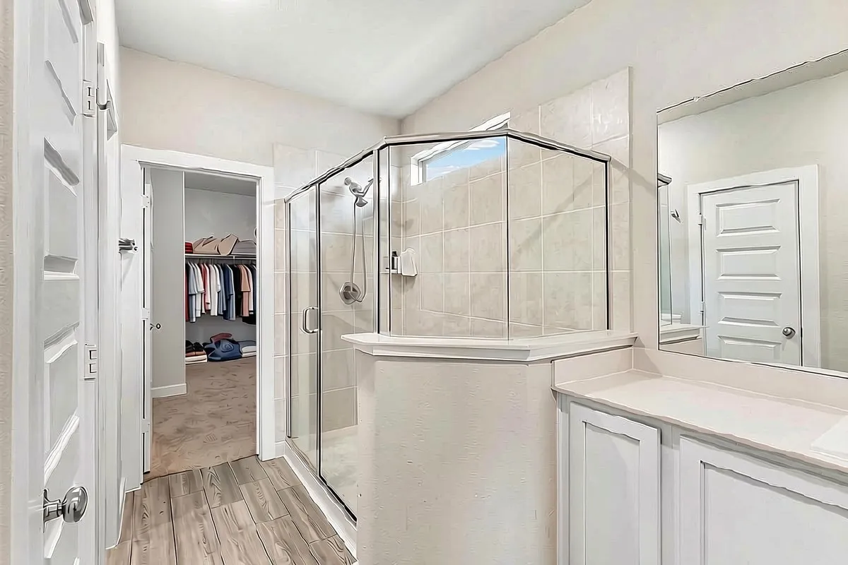 Walk-in shower with clear glass enclosure and tile surround