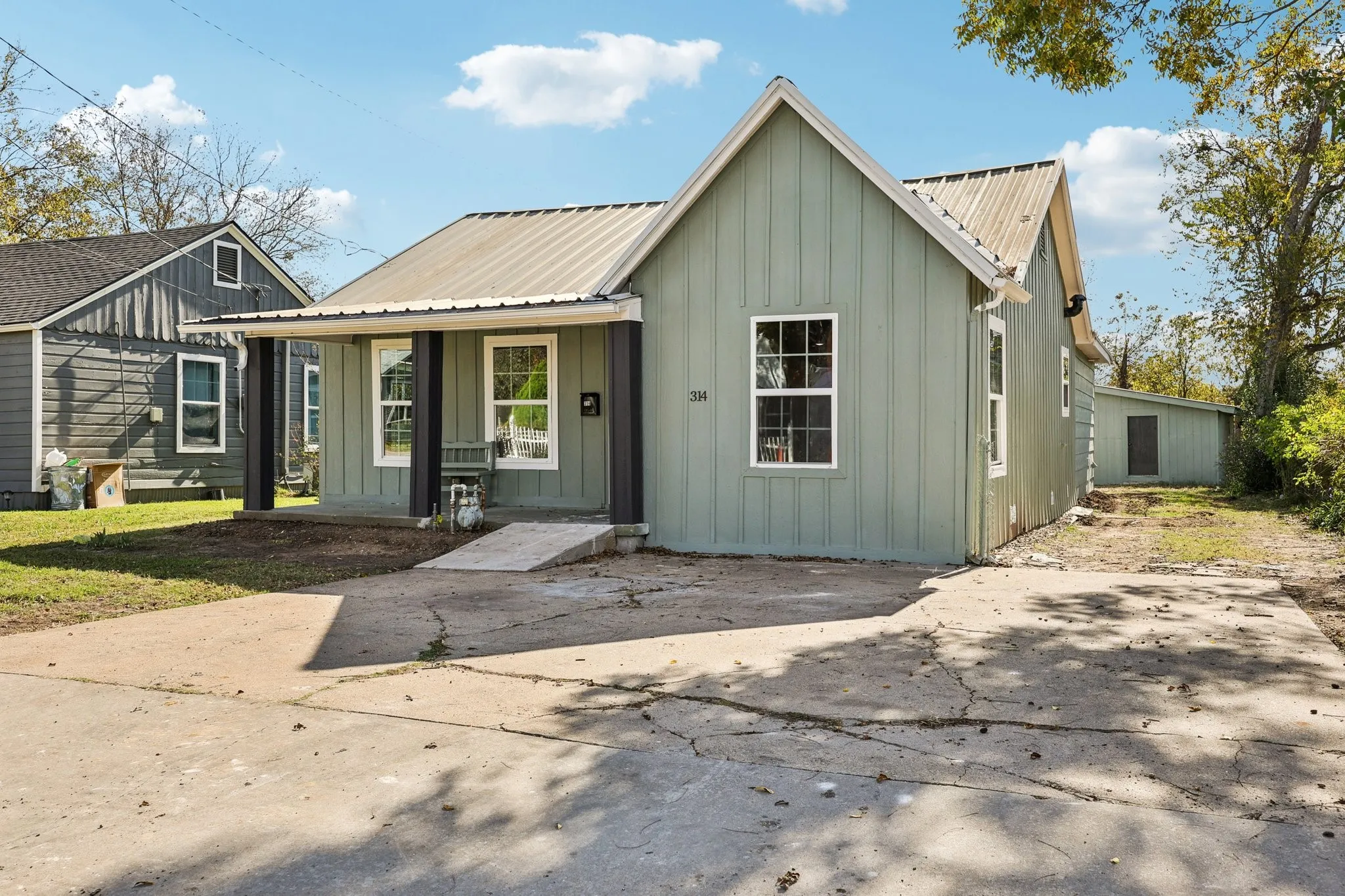 Light green board-and-batten siding with a corrugated metal roof