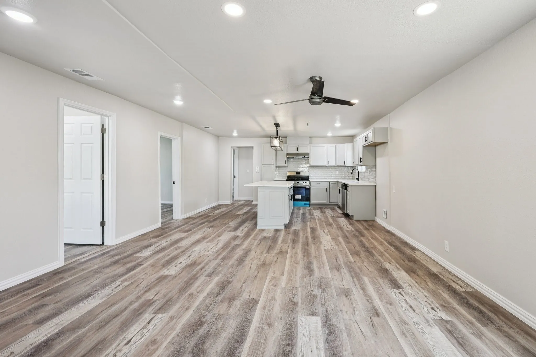 Open-concept living space featuring wood-finish flooring, recessed lighting, and a modern ceiling fan