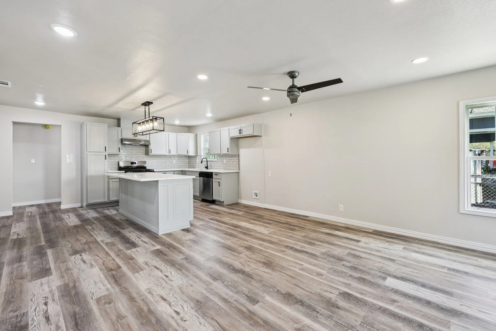 Open-concept living space featuring wood-finish flooring, recessed lighting, and a modern ceiling fan