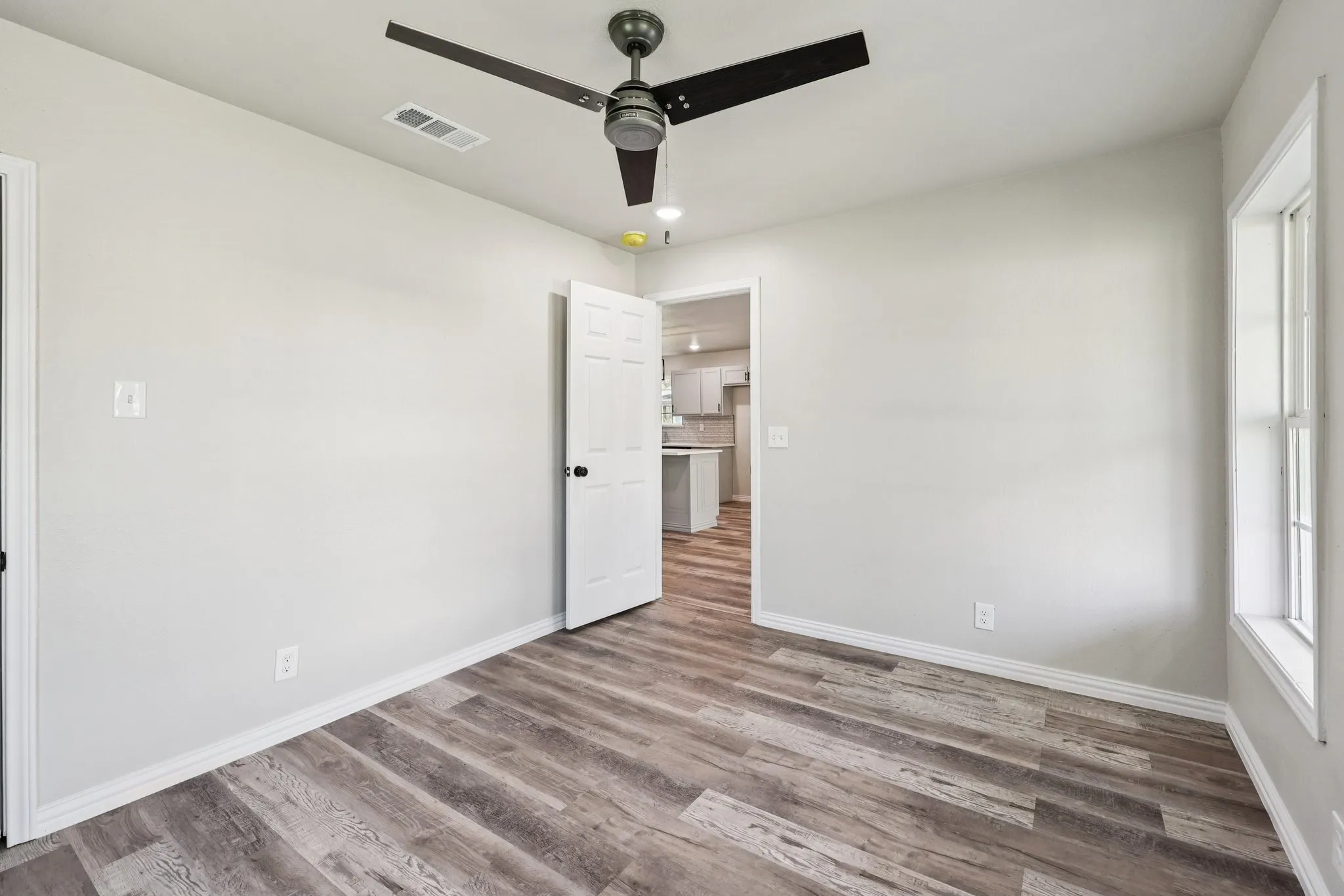 Interior room featuring wood-finish flooring, light gray wall paint, and white trim