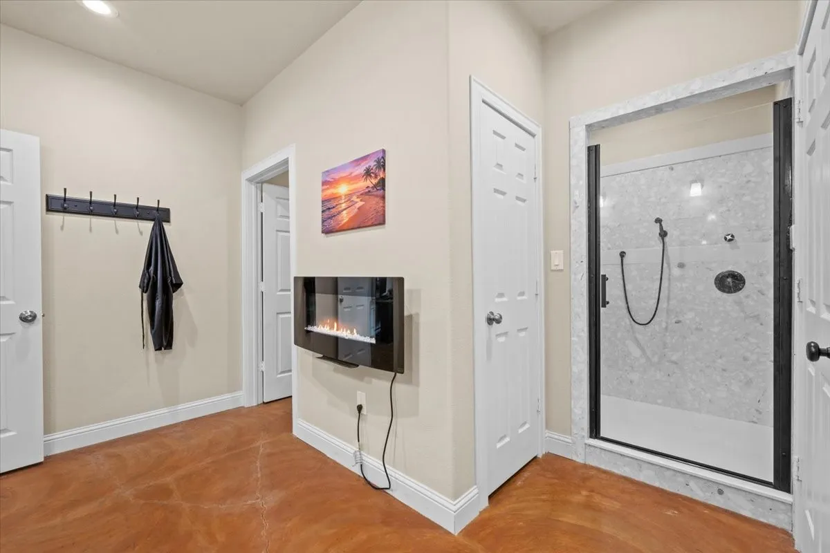 Primary bathroom with stained concrete floors, granite counters, separate shower, linen closet and huge walk-in closet at 3601 Oak Cir, Weatherford, TX 76088 - 3664 sq ft on 2.92 acres with a 2600 sq ft workshop