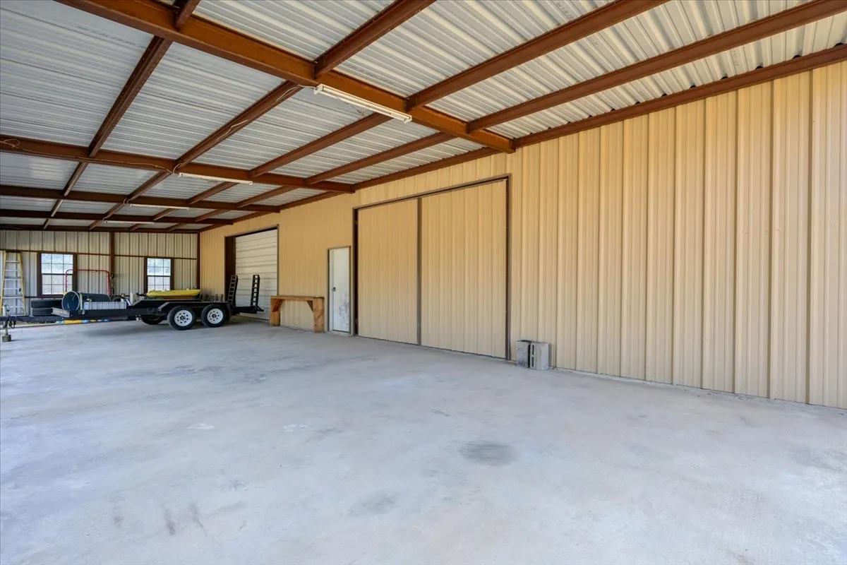 Expansive 2600 sq ft workshop equipped with large covered carport, a set of swing doors and an overhead door at 3601 Oak Cir, Weatherford, TX -76088 on 2.92 acres