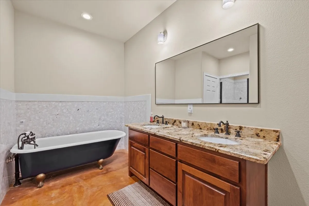 Primary bathroom with stained concrete floors, granite counters, separate shower, linen closet and huge walk-in closet at 3601 Oak Cir, Weatherford, TX 76088 - 3664 sq ft on 2.92 acres with a 2600 sq ft workshop