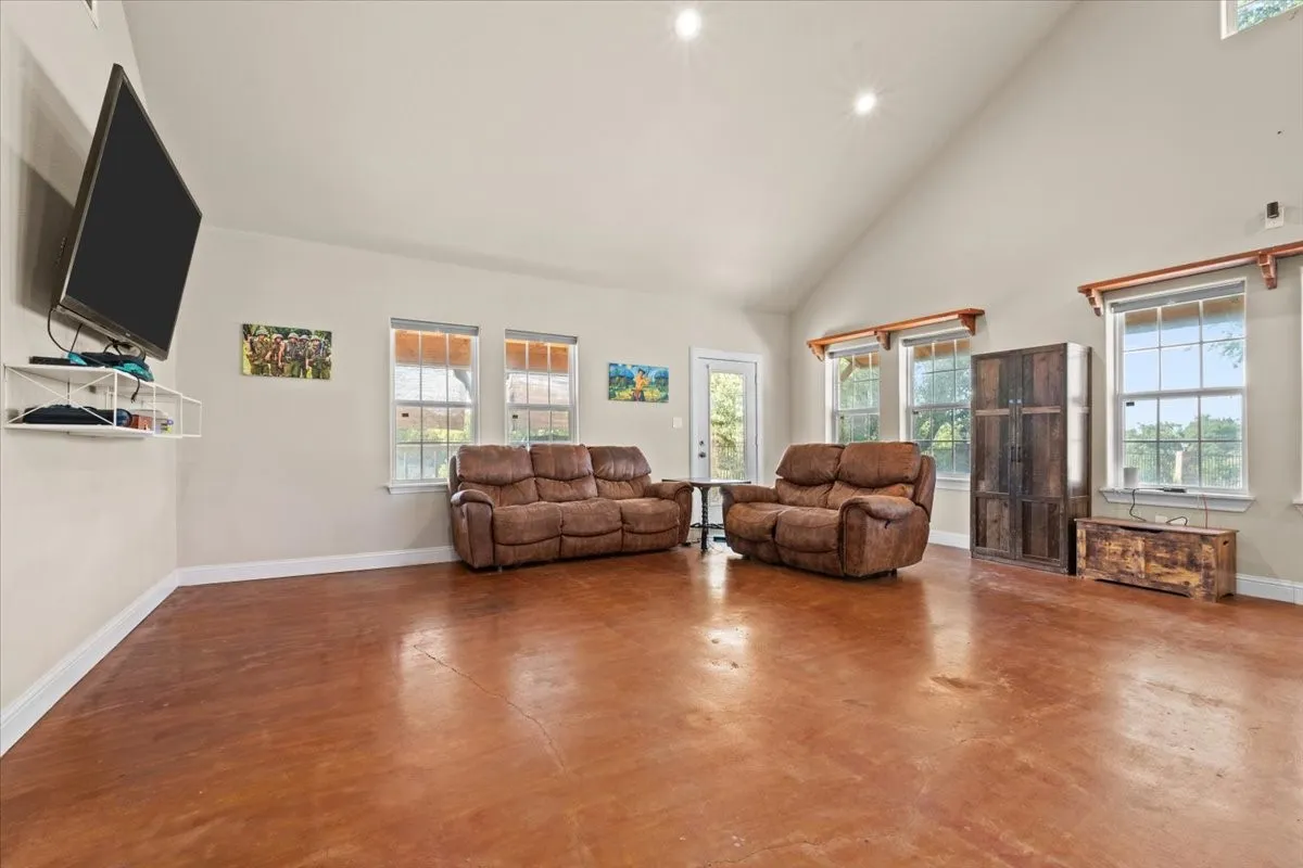 Spacious living room with stained concrete floors, vaulted ceiling and abundant natural light at 3601 Oak Cir, Weatherford, TX 76088 - 3664 sq ft on 2.92 acres with a 2600 sq ft workshop