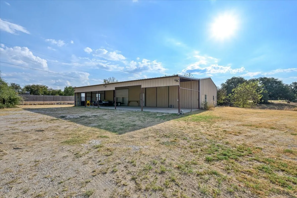 Expansive 2600 sq ft workshop equipped with large covered carport, a set of swing doors and an overhead door at 3601 Oak Cir, Weatherford, TX -76088 on 2.92 acres