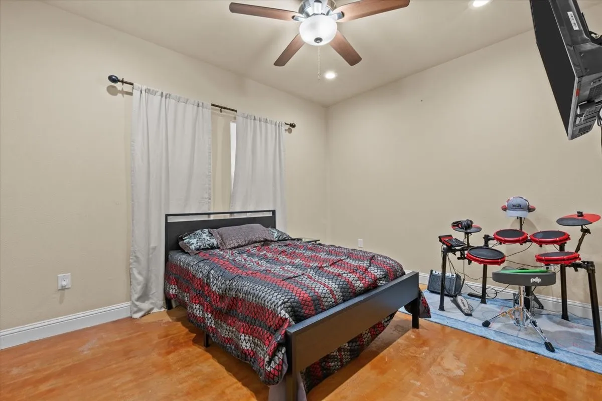 Bedroom with stained concrete floors at 3601 Oak Cir, Weatherford, TX 76088 - 3664 sq ft on 2.92 acres with a 2600 sq ft workshop