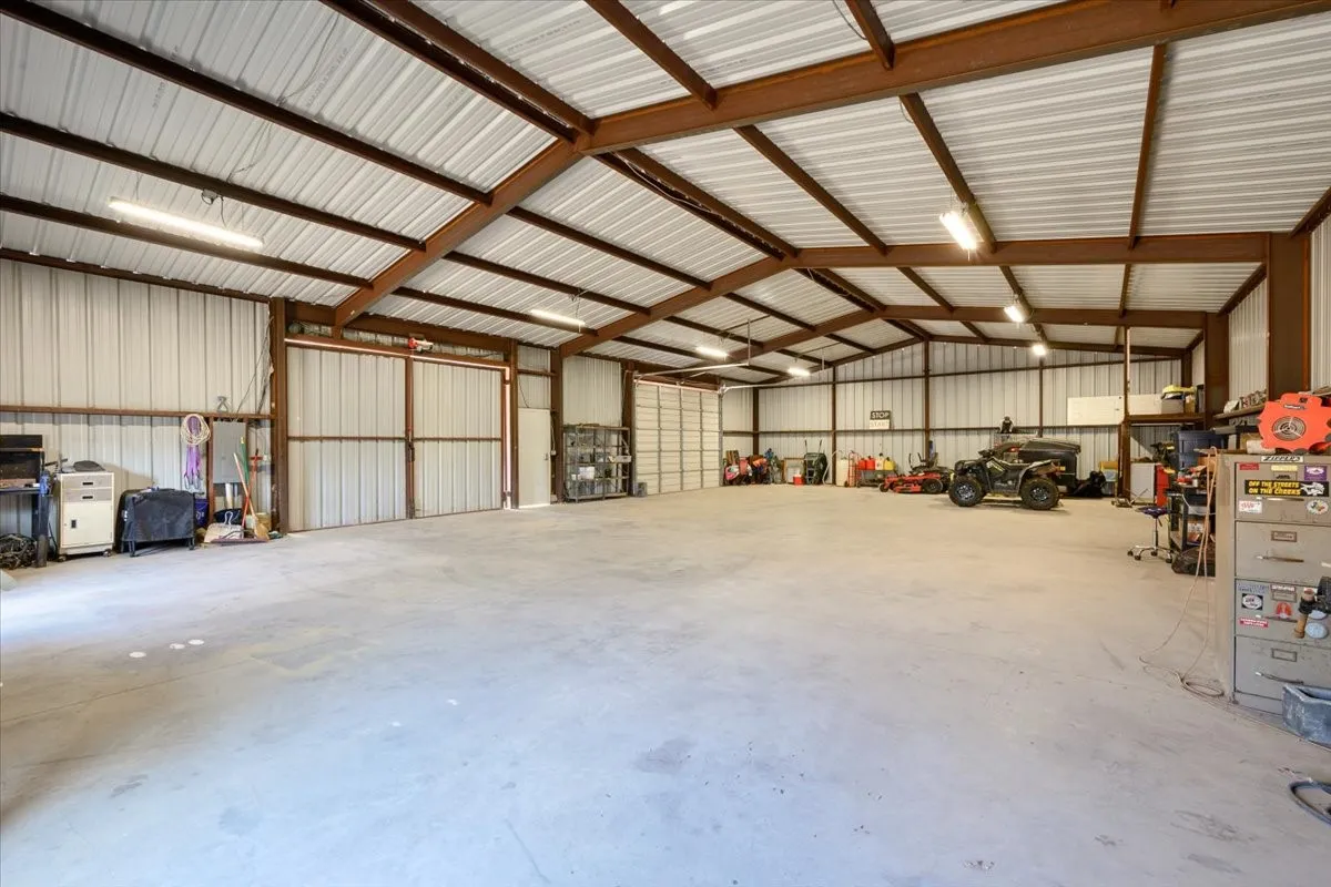 Expansive 2600 sq ft workshop equipped with set of swing doors and an overhead door at 3601 Oak Cir, Weatherford, TX -76088 on 2.92 acres