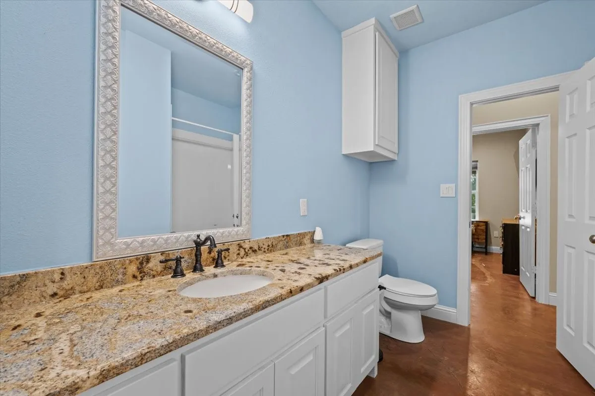 Bathroom with ganite countertops and stained concrete floors at 3601 Oak Cir, Weatherford, TX 76088 - 3664 sq ft on 2.92 acres with a 2600 sq ft workshop