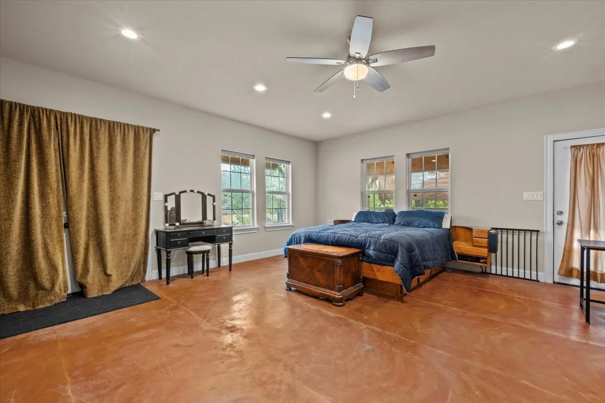 Spacious primary bedroom with stained concrete floors at 3601 Oak Cir, Weatherford, TX 76088 - 3664 sq ft on 2.92 acres with a 2600 sq ft workshop