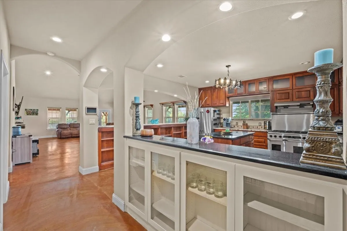 Large kitchen with stained concrete floors, island, granite counters, abundant cabinets, and commercial grade Dacor range at 3601 Oak Cir, Weatherford, TX 76088 - 3664 sq ft on 2.92 acres with a 2600 sq ft workshop