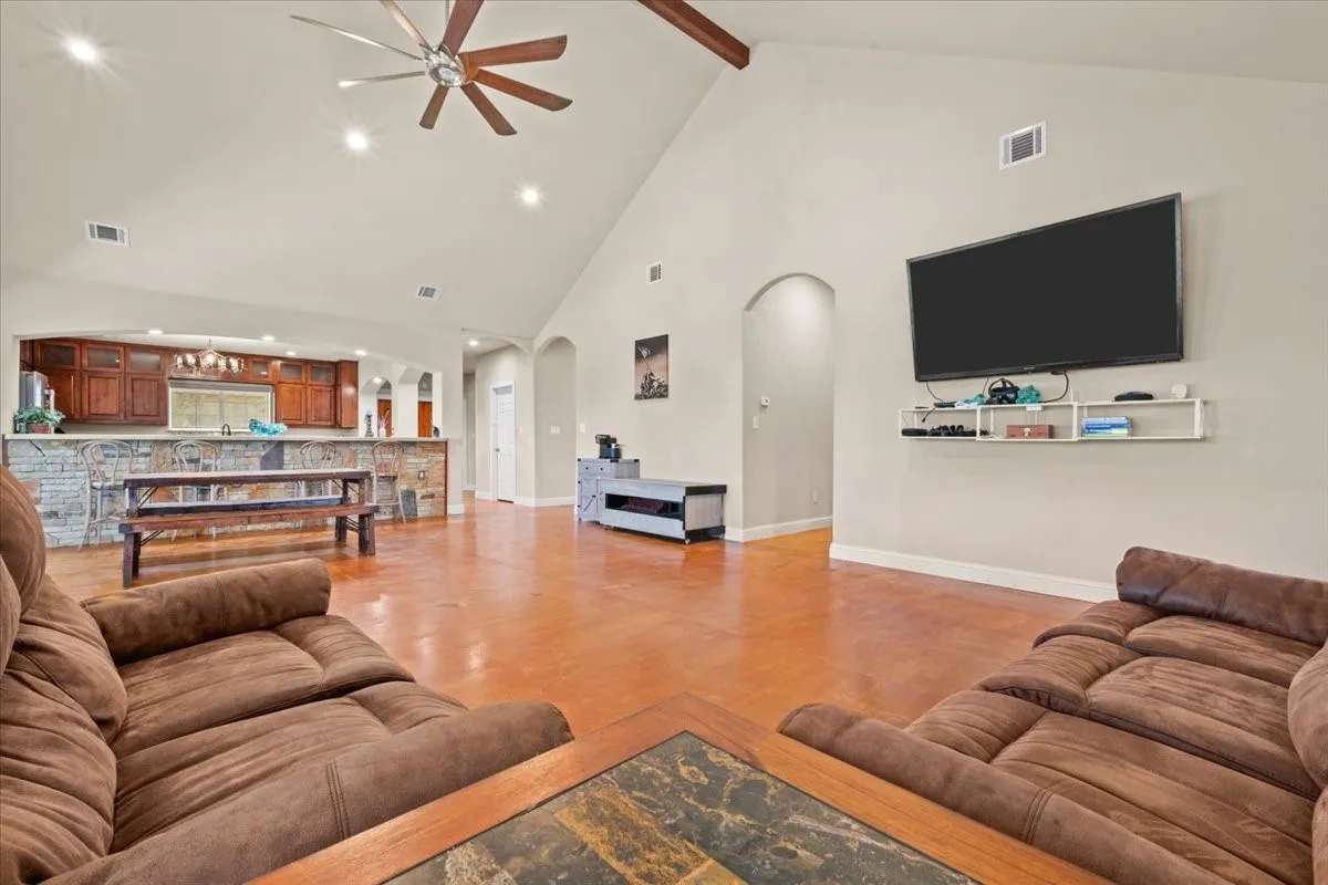 Spacious living room with stained concrete floors, vaulted ceiling, and abundant natural light at 3601 Oak Cir, Weatherford, TX 76088 - 3664 sq ft on 2.92 acres with a 2600 sq ft workshop