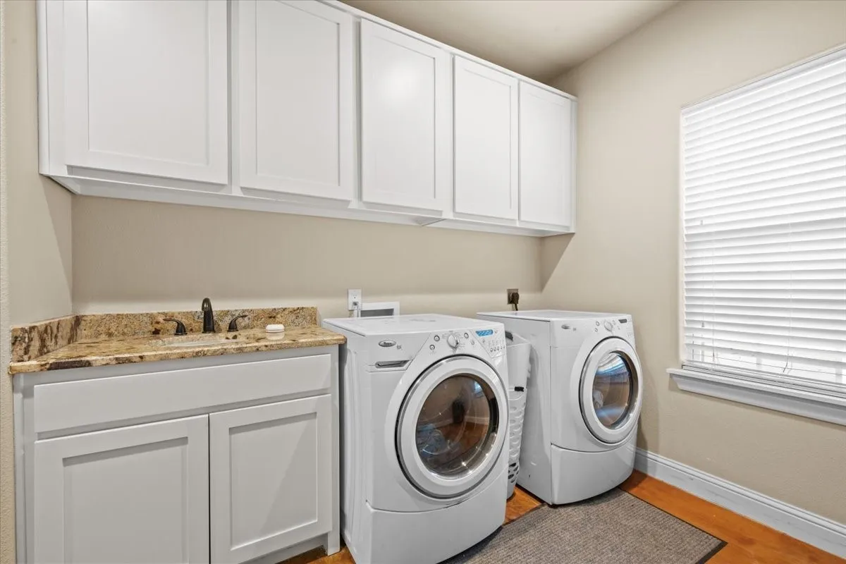 Large laundry room with cabinets, sink and extra room for refrigerator at 3601 Oak Cir, Weatherford, TX 76088 - 3664 sq ft on 2.92 acres with a 2600 sq ft workshop
