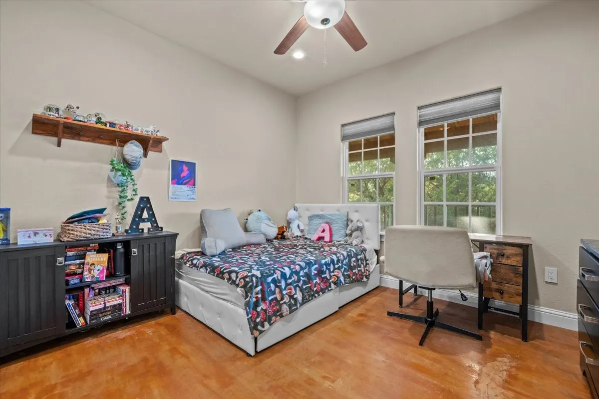 Bedroom with stained concrete floors and walk in closet at 3601 Oak Cir, Weatherford, TX 76088 - 3664 sq ft on 2.92 acres with a 2600 sq ft workshop