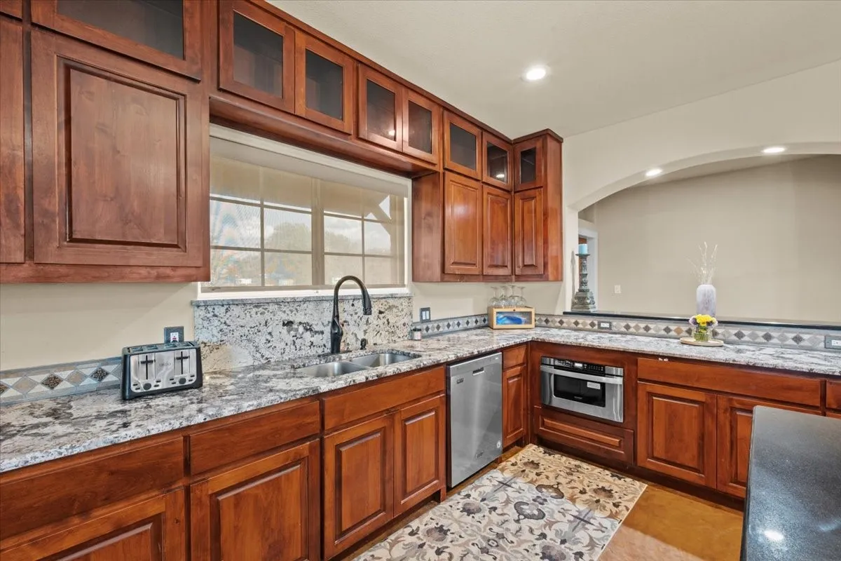 Large kitchen with stained concrete floors, island, granite counters, abundant cabinets, and commercial grade Dacor range at 3601 Oak Cir, Weatherford, TX 76088 - 3664 sq ft on 2.92 acres with a 2600 sq ft workshop