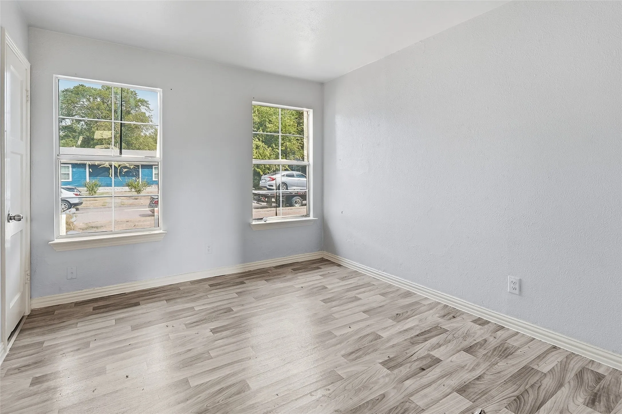 Wood-finish flooring, white trim, and light gray wall paint
