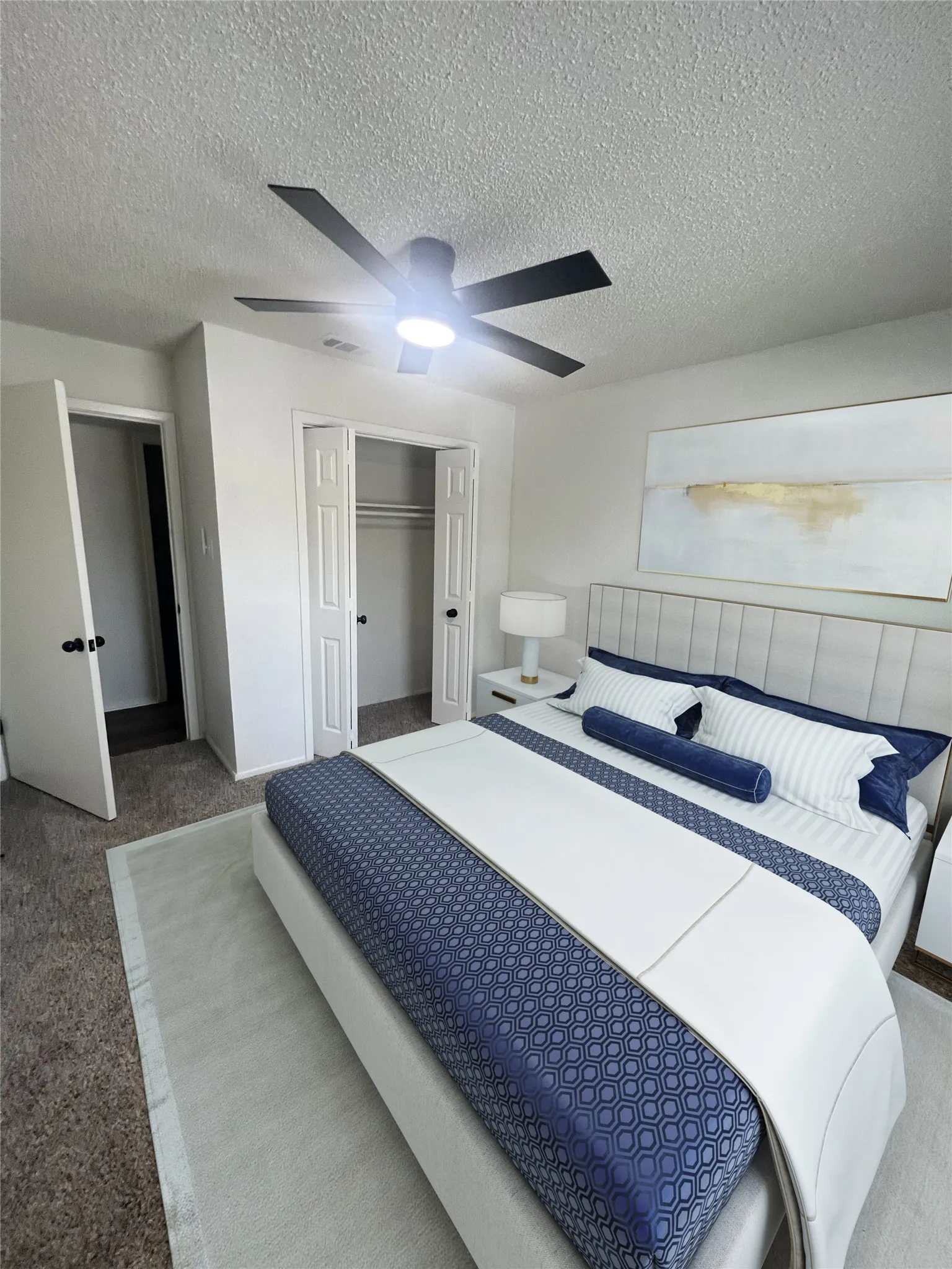 Carpeted bedroom featuring a textured ceiling, a closet, and ceiling fan