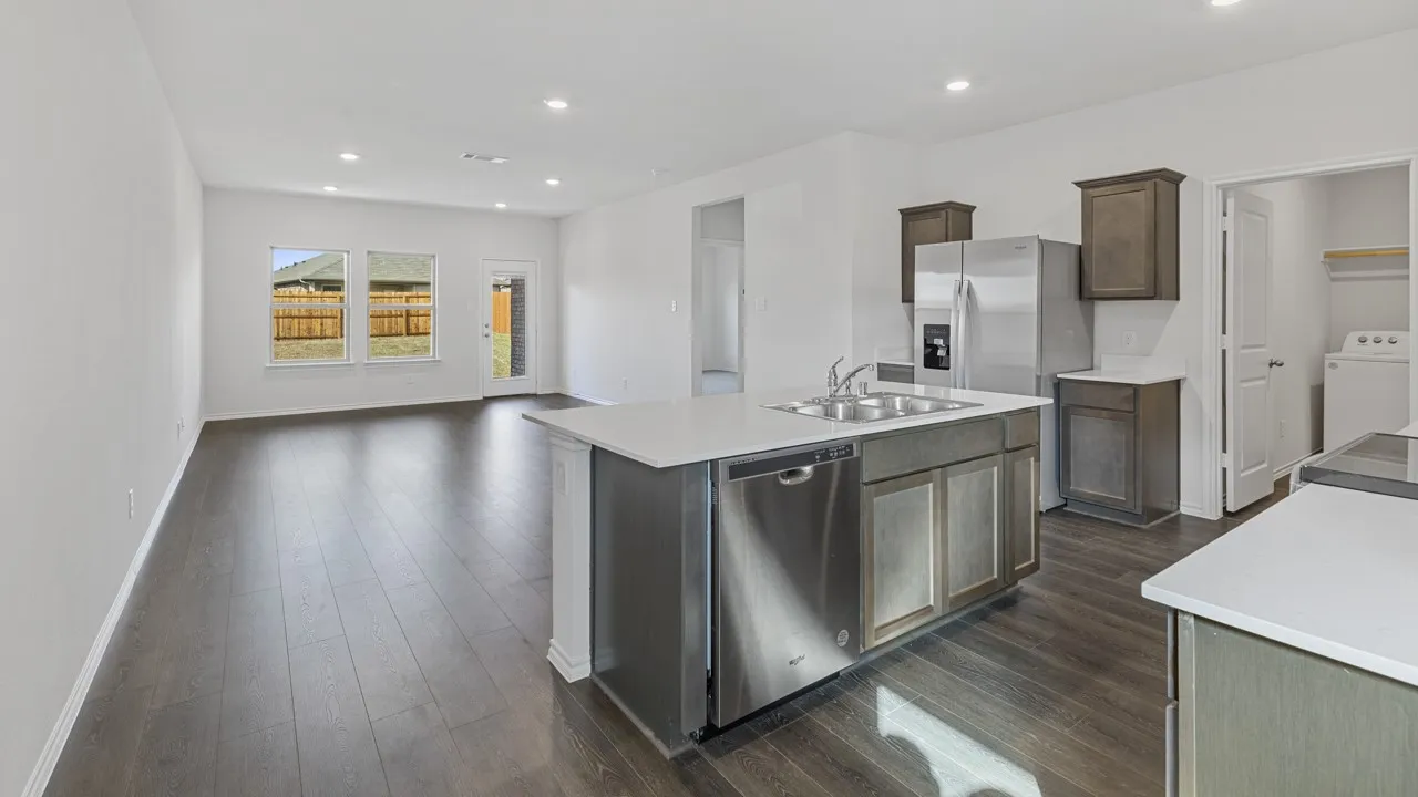 Kitchen featuring stainless steel appliances, a center island with sink, and white countertops
