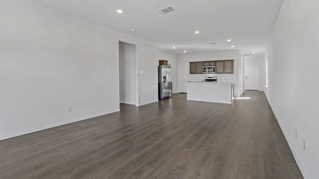 Open-concept living space featuring wood-finish flooring, recessed lighting, white walls, and a kitchen with stainless steel appliances and wood cabinetry