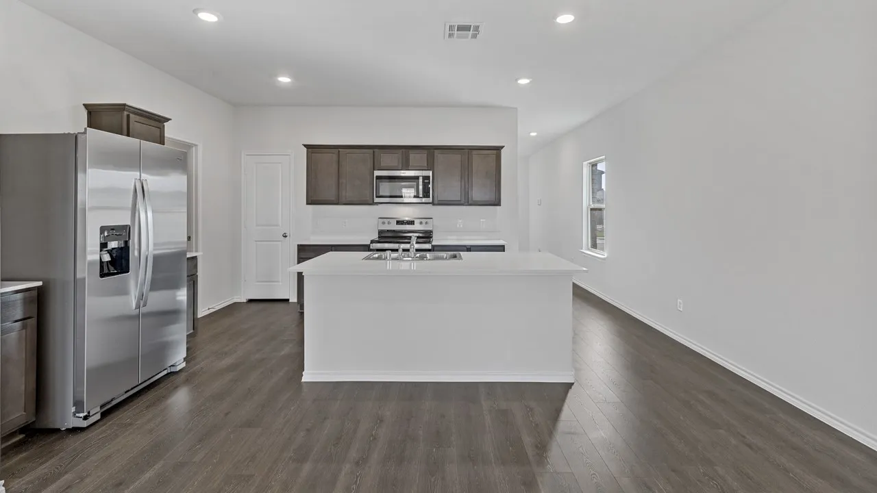Kitchen featuring dark wood-finish cabinetry, stainless steel appliances, a center island with sink, white countertops, and wood-finish flooring