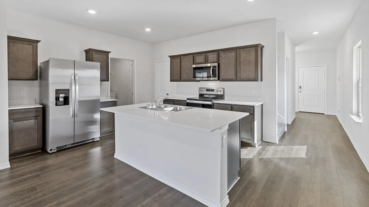Contemporary kitchen featuring dark wood-finish cabinetry, white countertops, stainless steel appliances, and wood-finish flooring