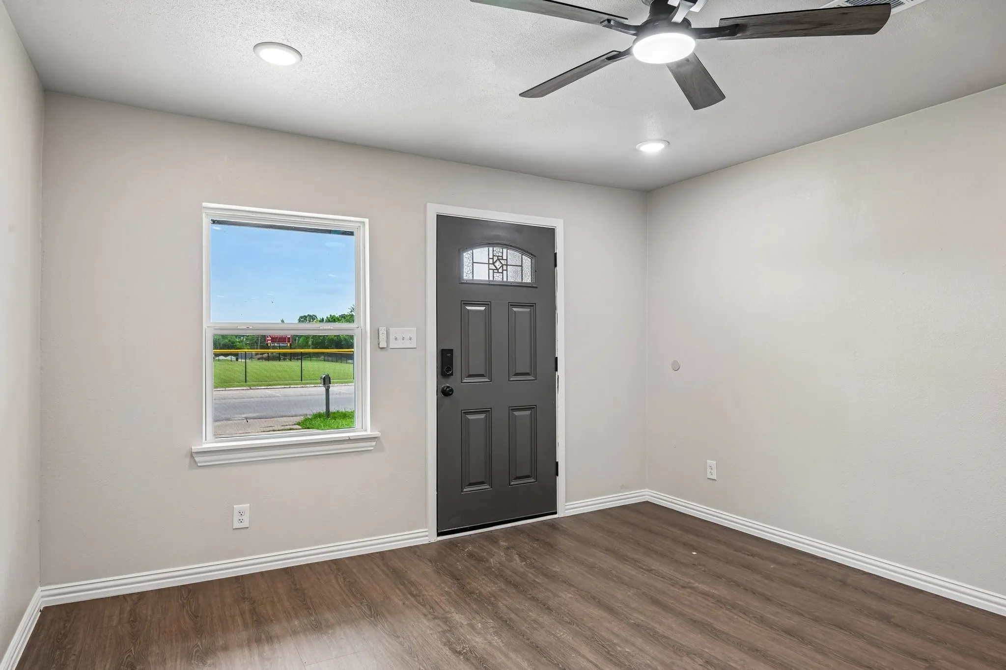 Entryway featuring wood-finish flooring, a contemporary ceiling fan with integrated lighting, two recessed ceiling lights, and a dark-paneled door with decorative glass inserts