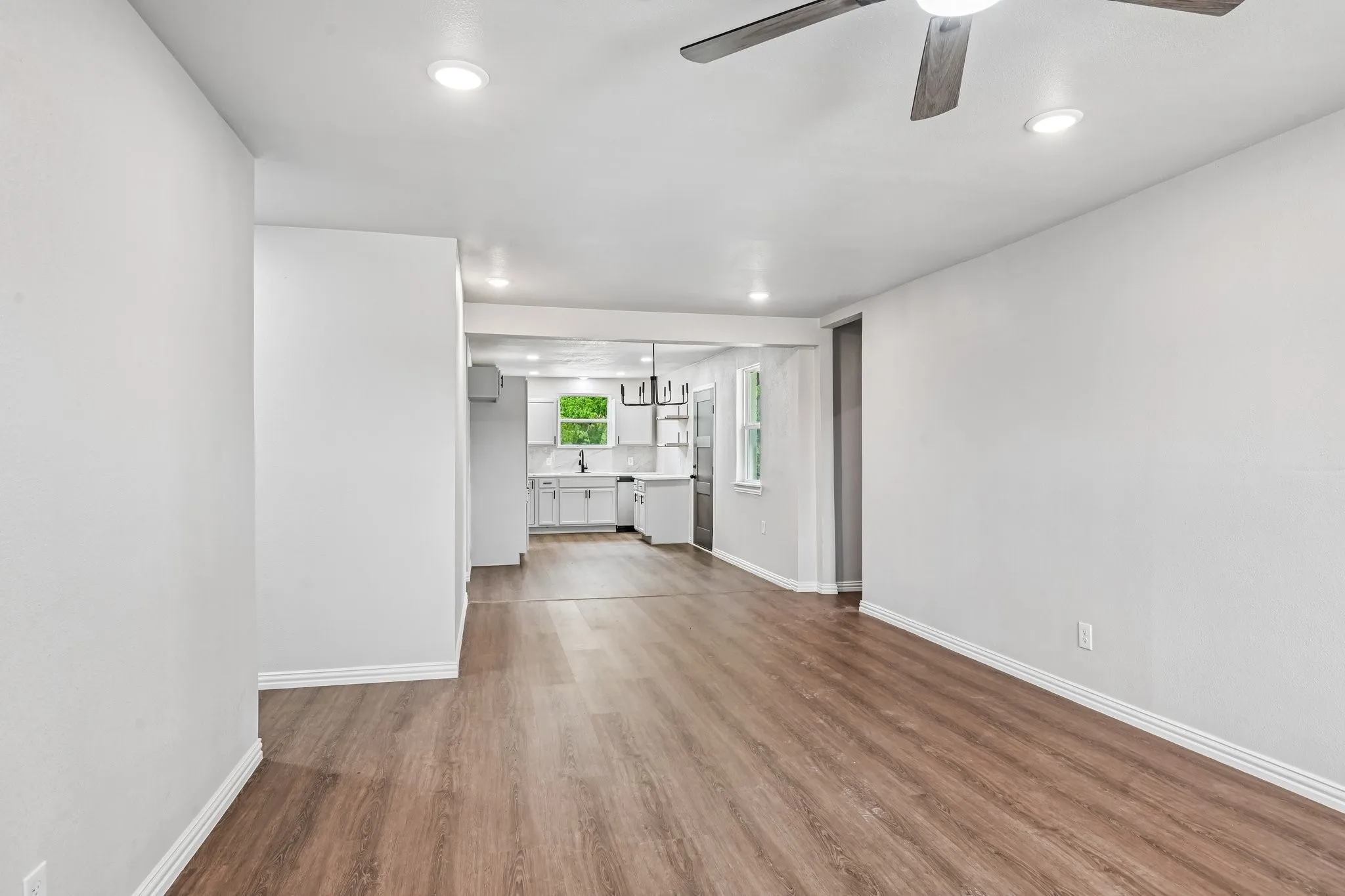 Expansive living area with wood-finish flooring, recessed lighting, and a ceiling fan