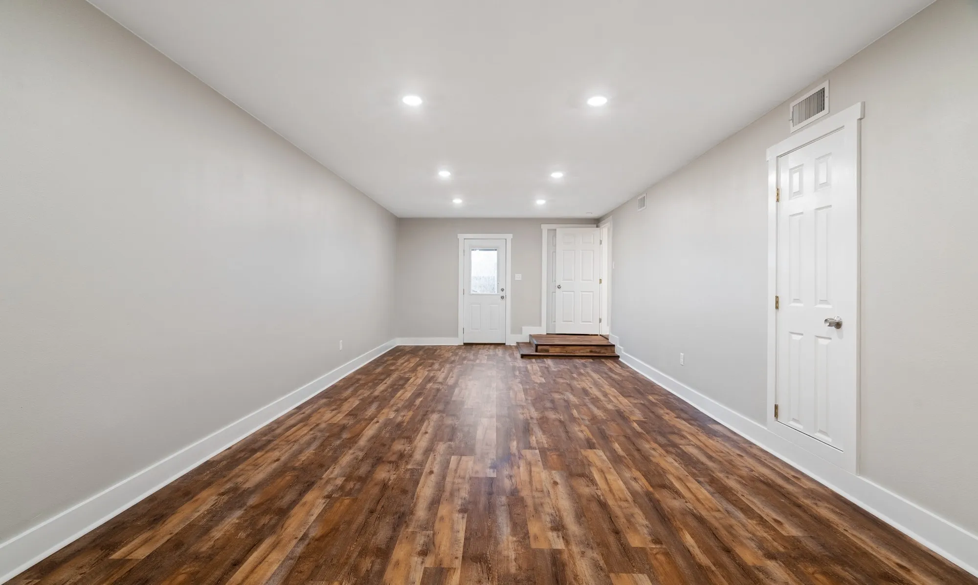 Spacious room featuring wood-finish flooring, recessed lighting, and light-toned wall finishes