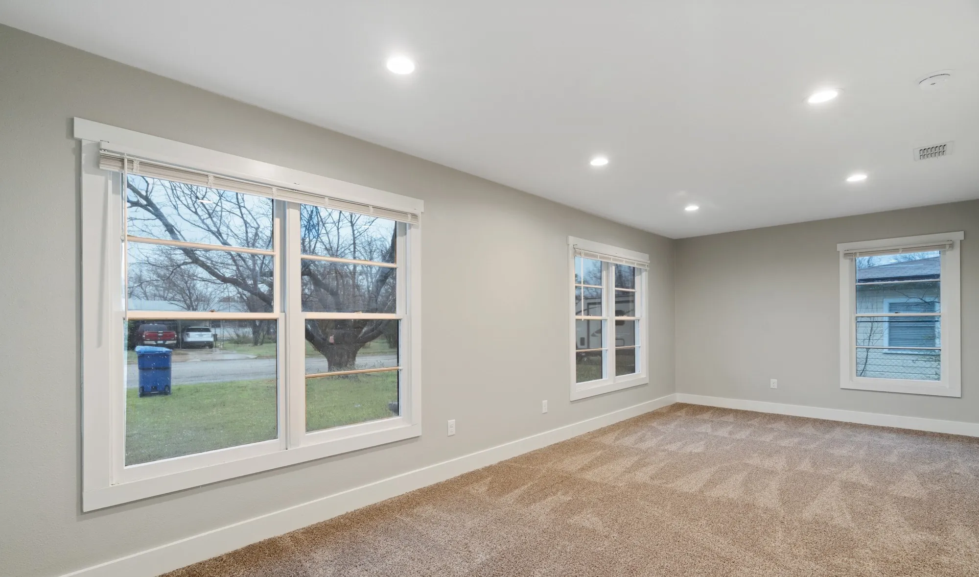 Recessed lighting, light gray walls, white trim, multiple windows, and carpeted flooring