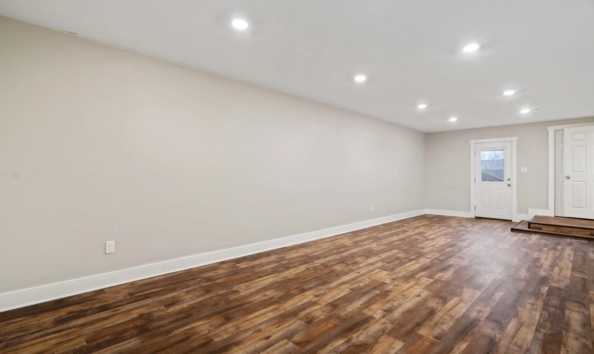 Recessed lighting, wood-finish flooring, light-toned walls, and white trim