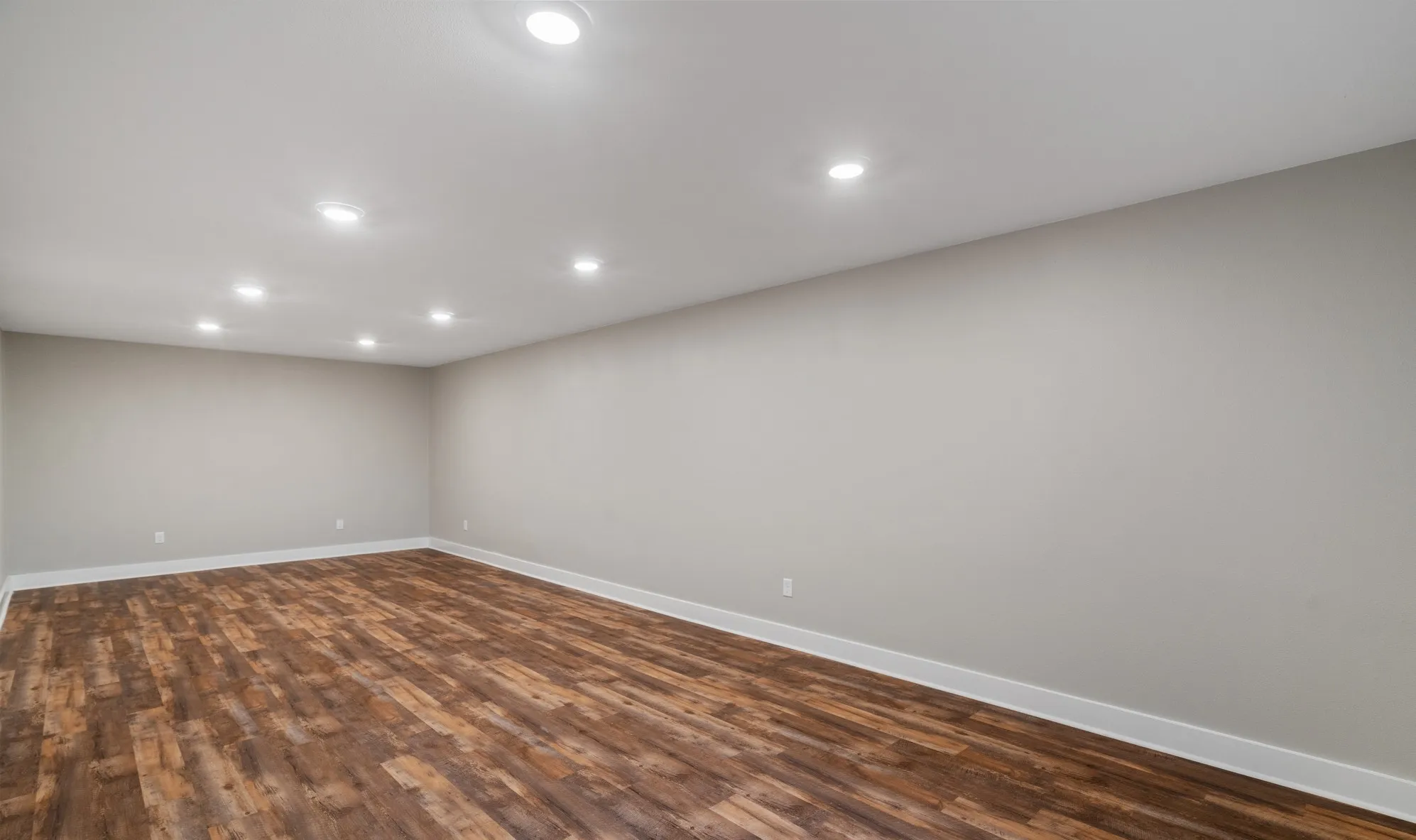 Spacious room with wood-finish flooring, recessed lighting, and light-toned walls