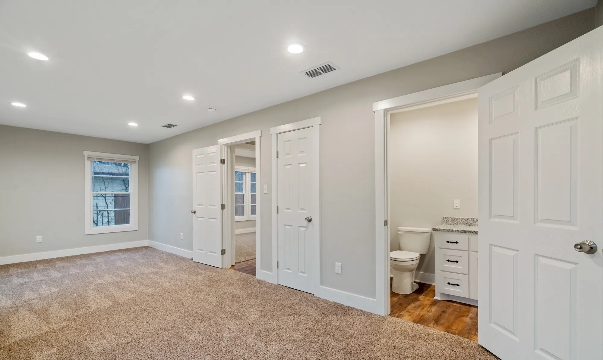 Spacious room with plush carpet, recessed lighting, and a window providing natural light