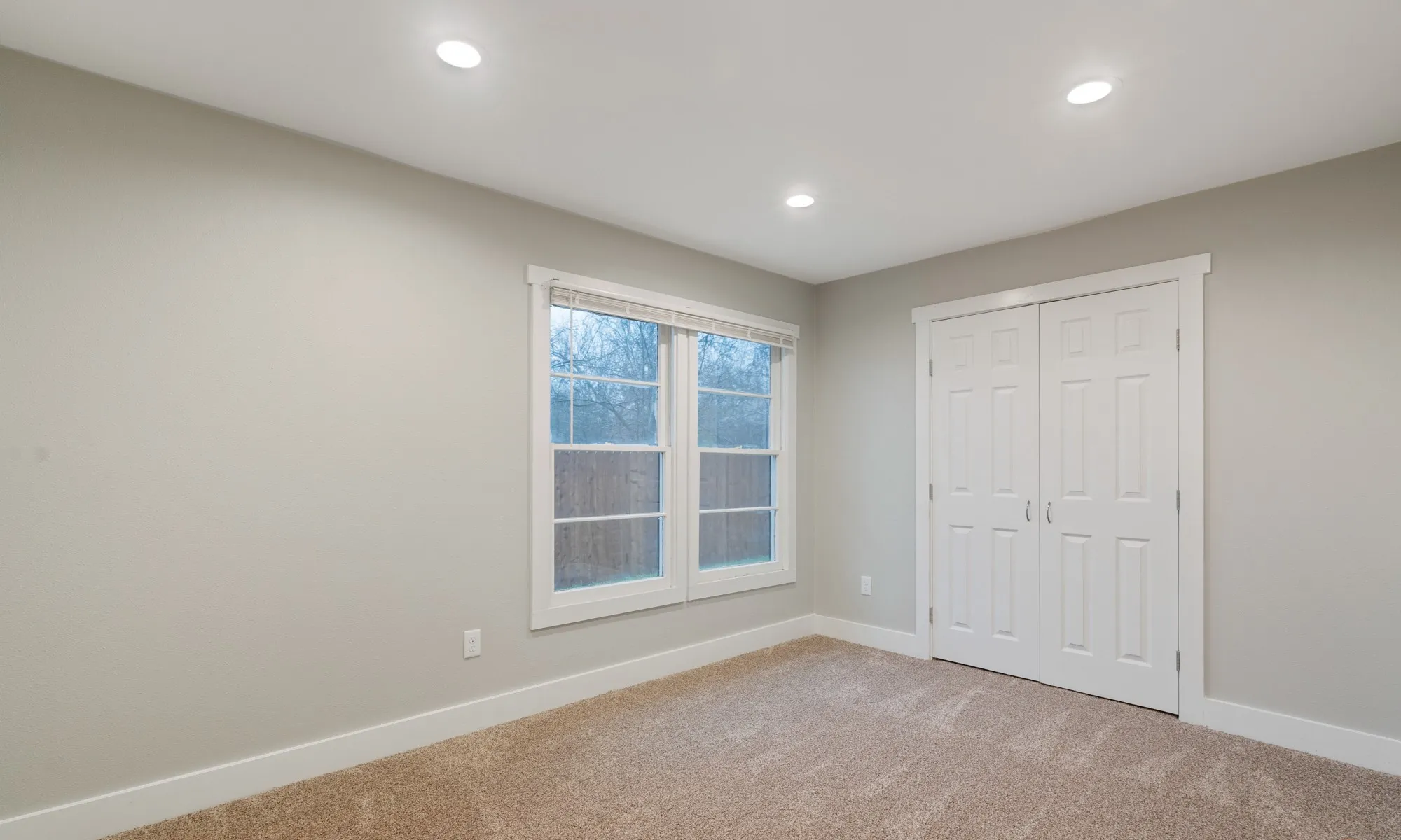 Recessed ceiling lighting, neutral wall tones, carpeted flooring, white trim, and a double-panel bifold door