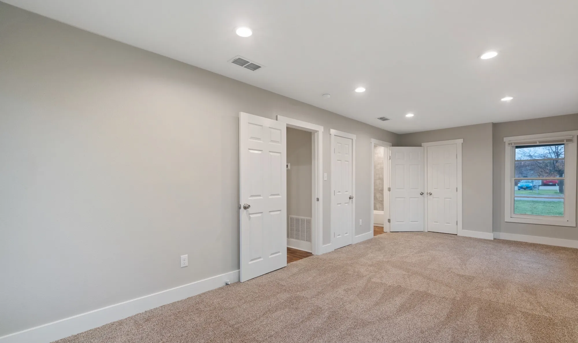 Recessed lighting, light-toned carpeting, neutral wall colors, white trim, and paneled doors